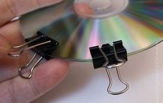 a hand holding a cd with two clips attached to it