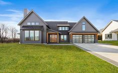 a large gray house sitting on top of a lush green field