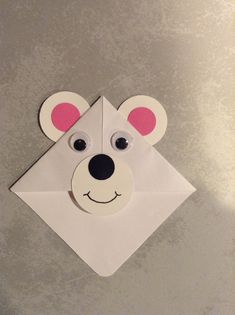 an origami bear head on top of a piece of white paper with pink ears