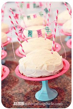 there is a cake on the table with pink and blue plates in front of it