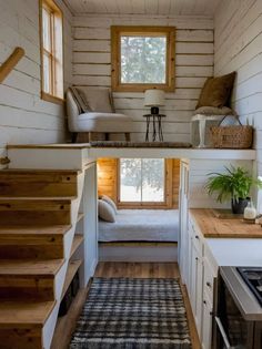 the interior of a tiny house with stairs leading up to the bed and kitchen area