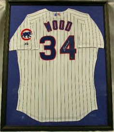 an autographed chicago cubs jersey is displayed in a shadow box on the wall