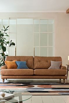 a living room with a couch, coffee table and potted plant