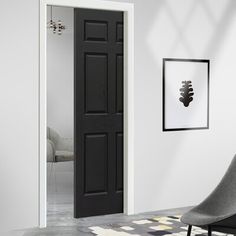 an empty living room with a chair and black door