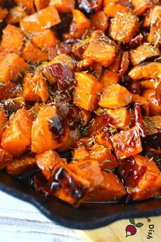 a pan filled with cooked sweet potatoes covered in balk and seasoning sitting on top of a wooden cutting board