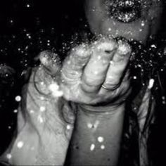 a black and white photo of someone holding their hands in the air with snow all over them