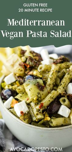 a white bowl filled with pasta salad and topped with olives, parmesan cheese and other toppings