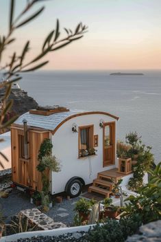 a tiny house on the side of a cliff by the ocean with plants growing out of it