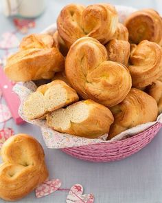 a pink basket filled with heart shaped pastries on top of a blue table cloth