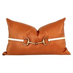 a brown pillow with two gold rings on the front and side, sitting on a white background