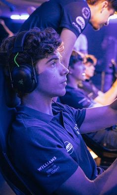 a man sitting in front of a computer monitor wearing headphones and holding a game controller