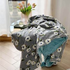 a blanket on a table next to a vase with flowers