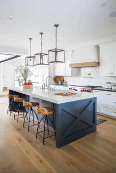 a kitchen island with four stools in front of it and a center island that has three barstools