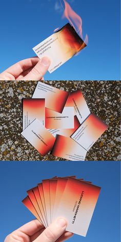 a person holding up some business cards with flames on the top and bottom, against a blue sky