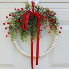 a wreath hanging on the front door decorated with red berries and greenery for christmas