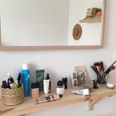 a wooden table topped with lots of cosmetics and personal care items next to a mirror