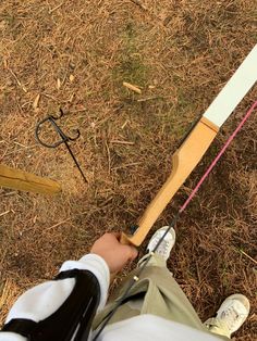 a person is holding a bow and aiming it at an object on the ground with grass