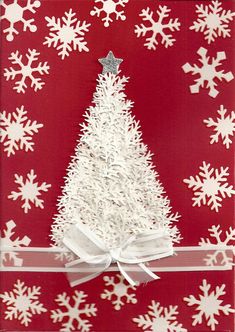 a red and white card with a christmas tree on it's side, surrounded by snowflakes