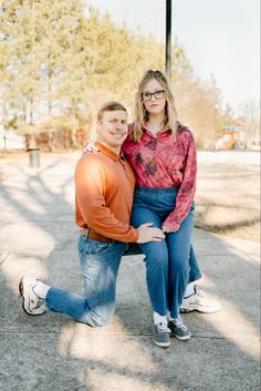 a man and woman sitting on a bench in front of a street light with their arms around each other