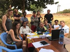 a group of people sitting around a table with laptops and papers on top of it