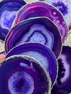 purple and white agate glass bowls sitting on top of a wooden table