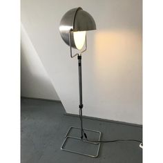 a lamp that is on top of a metal stand in front of a white wall