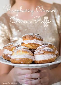 a woman holding a plate with donuts on it and powdered sugar on top