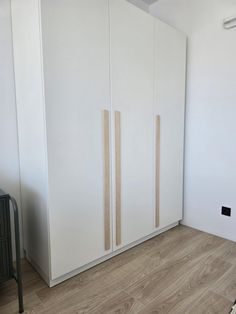 an empty room with white cupboards and wood flooring