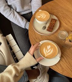 two people sitting at a table with cups of coffee