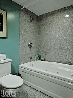 a white toilet sitting next to a bath tub in a bathroom under a framed painting