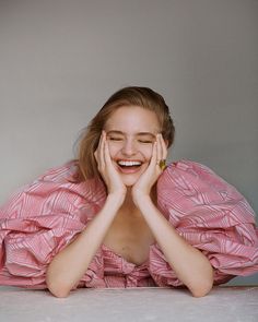 a woman laying on the floor with her hands under her face and smiling at the camera