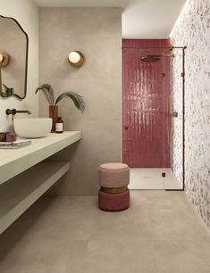 a bathroom with a pink shower and white counter top next to a mirror on the wall