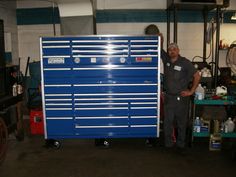 a man standing next to a blue tool cabinet