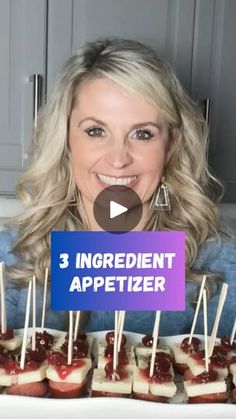 a woman is holding up some appetizers with toothpicks in front of her