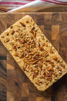 a wooden cutting board topped with pecans and caramel