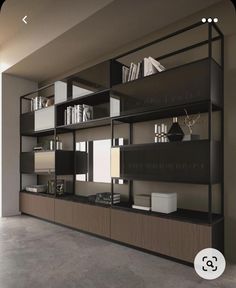 a large bookcase with many books on it in an empty room next to a window