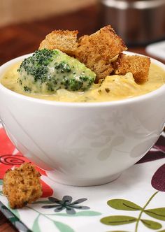 a white bowl filled with broccoli and croutons on top of a table