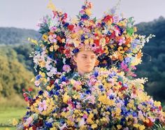 a woman with flowers on her head in the middle of a field