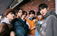 a group of young men standing next to each other in front of a brick building