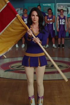 a woman holding a flag in front of a group of people on a basketball court