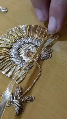 someone is working on something that looks like a brooch