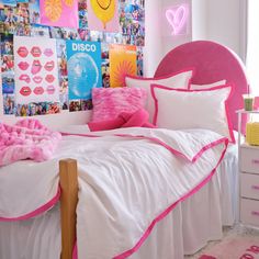 a pink and white bedroom with pictures on the wall above the bed, along with pillows