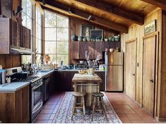 a kitchen with wooden walls and flooring next to a stove top oven