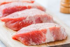 two raw pork chops sitting on top of a cutting board