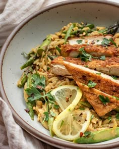 a white bowl filled with chicken, rice and lemons on top of a table