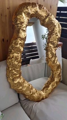 a gold mirror sitting on top of a white couch