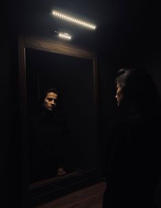 a man standing in front of a mirror looking at his own reflection on the wall