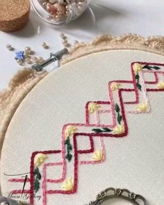 a close up of a piece of embroidery on a table with scissors and other items