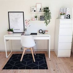 a white desk and chair in a room with wood flooring, framed pictures on the wall