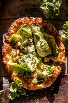 a pizza sitting on top of a wooden table covered in cheese and veggies